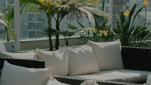 Ein Balkon mit einer Couch und Topfpflanzen mit Blick auf eine Stadtansicht.