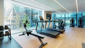 Ein modernes Fitnessstudio mit Laufbändern, Crosstrainern und Kurzhanteln.