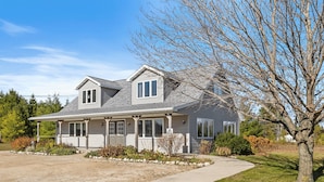 A two-story house with a covered porch, a garage, and a driveway. - Perfect Retreat for 2 | Studio Above Bakery, Dogs! (Sister Bay)