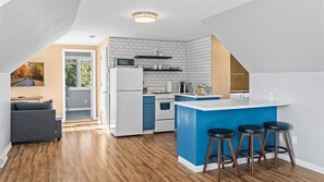 Una cocina moderna con una isla azul, electrodomésticos blancos y vistas al exterior.