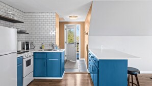 A modern kitchen with white and blue cabinetry, a built-in oven, and a white countertop. - Perfect Retreat for 2 | Studio Above Bakery, Dogs! (Sister Bay)