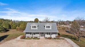A two-story house with a central entrance, a driveway, and a surrounding landscape. - Perfect Retreat for 2 | Studio Above Bakery, Dogs! (Sister Bay)