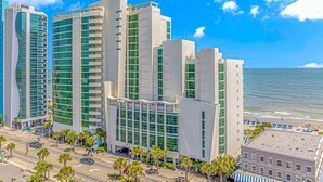 Een modern hotel met meerdere hoge gebouwen, uitzicht op het strand en een heldere lucht.