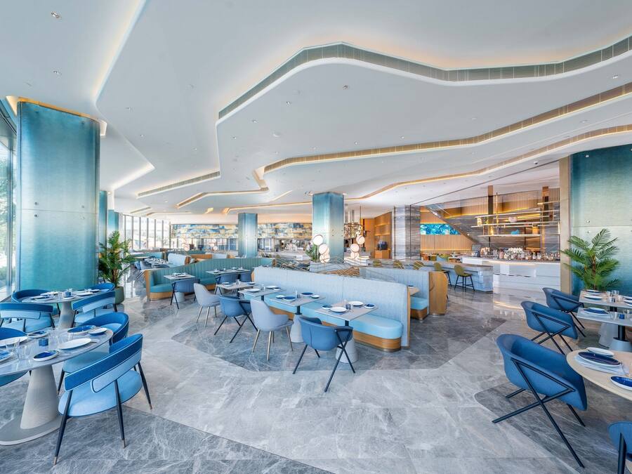 Un restaurant moderne avec des sièges bleus, des sols en marbre et un aménagement spacieux.
