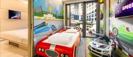 Habitación infantil con temática de carreras, que incluye una cama, un coche de juguete y murales de carreras en las paredes.
