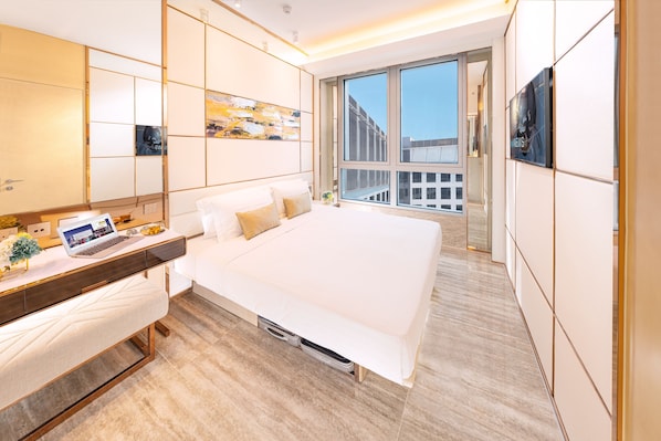 A modern hotel room with a large bed, a desk with a laptop, and a view of the city through large windows. - Regala Skycity Hotel by Regal Hotels (Chek Lap Kok)