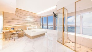 Un dormitorio moderno con una cama grande, un escritorio y vistas de la ciudad.