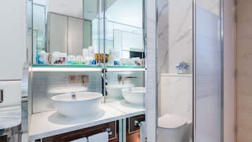 Un baño moderno con un espejo grande, dos lavamanos, un inodoro y una zona de ducha.