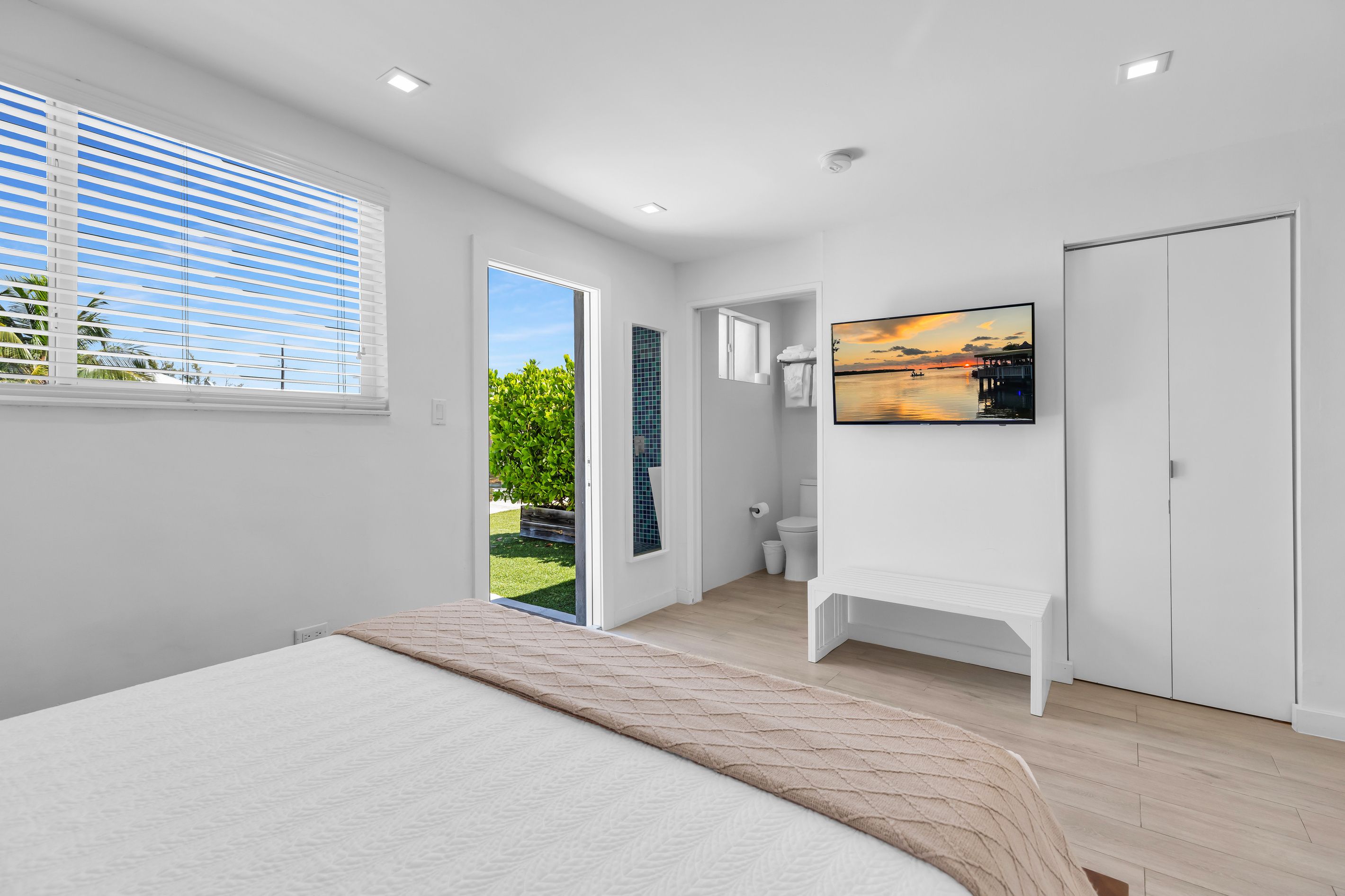 Un dormitorio moderno con cama, televisor y baño completo.