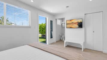 Un dormitorio moderno con cama, televisor y baño completo.