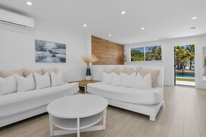 A modern living room with two white sofas, a round coffee table, and a wooden accent wall.