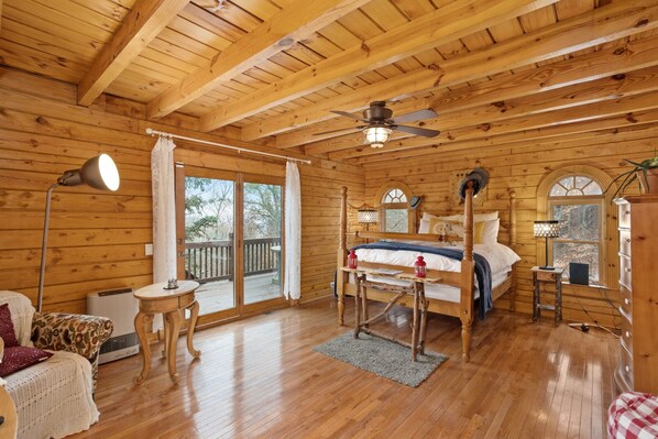 A cozy log cabin bedroom with a bed, a desk, a chair, and a window.