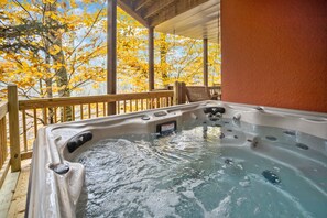 Ein Whirlpool auf einer Holzterrasse mit Blick auf Herbstbäume.