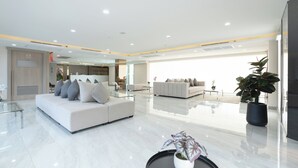 A spacious, modern living area with a large sofa, a coffee table, and a potted plant. - Oriole Residence (Bang Phli)
