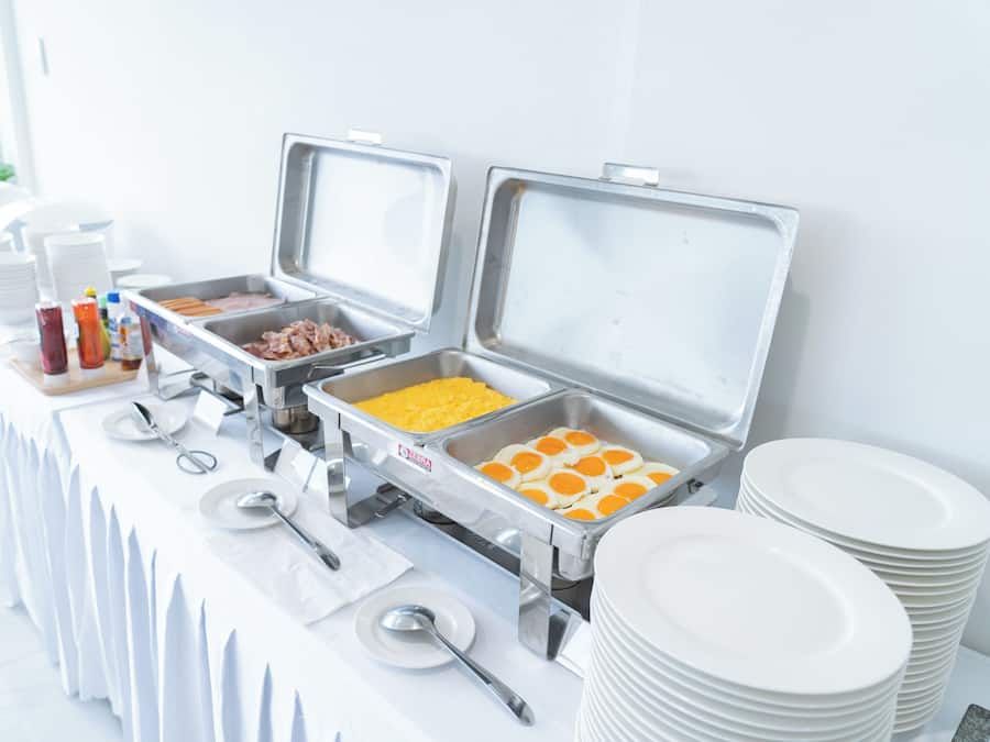 A buffet setup with various food items and utensils.