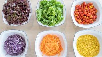 Tres tazones con distintos alimentos: repollo morado rallado, zanahorias naranjas ralladas y granos de maíz amarillo.