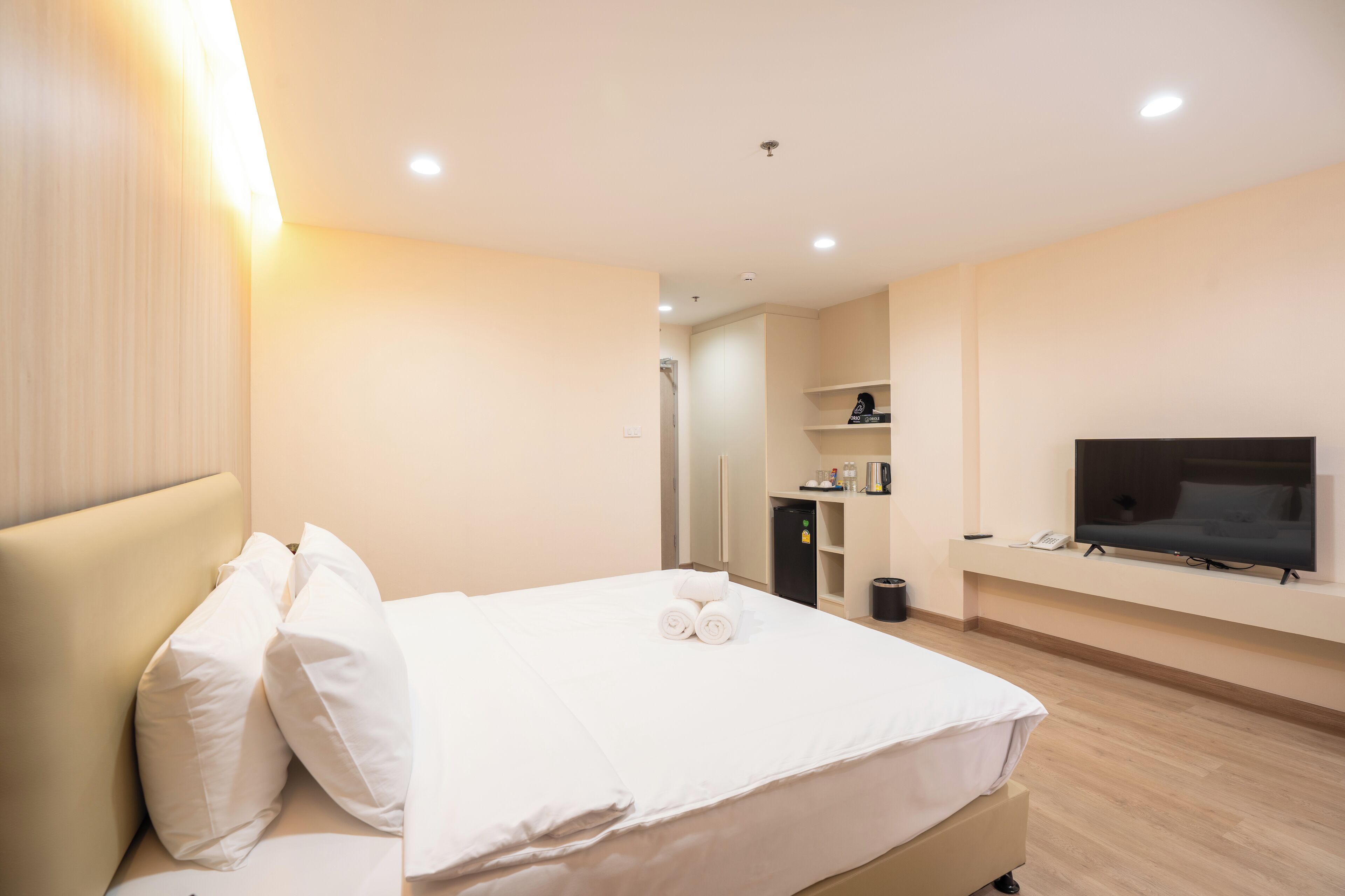 Una habitación de hotel con una cama, un televisor en la pared y una pequeña zona de kitchenette.