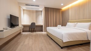A hotel room with a bed, a desk, a chair, a television, and a telephone. - Oriole Residence (Bang Phli)