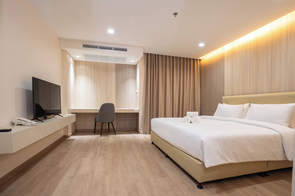 A hotel room with a bed, a desk, a chair, a television, and a telephone.