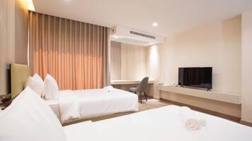 Een hotelkamer met twee bedden, een bureau, een stoel, een televisie en een airconditioner.