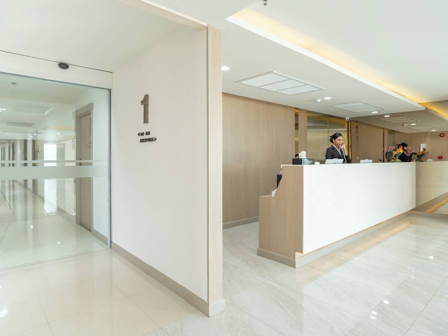 A modern reception area with a glass wall, a reception desk, and a sign indicating room number 1.