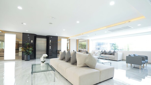 A modern living room with a beige sofa, glass coffee table, and a potted plant. - Oriole Residence (Bang Phli)