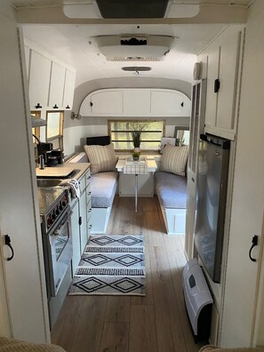 Eine kleine Küchenzeile für ein Wohnmobil, mit Herd, Spüle und Kühlschrank.
