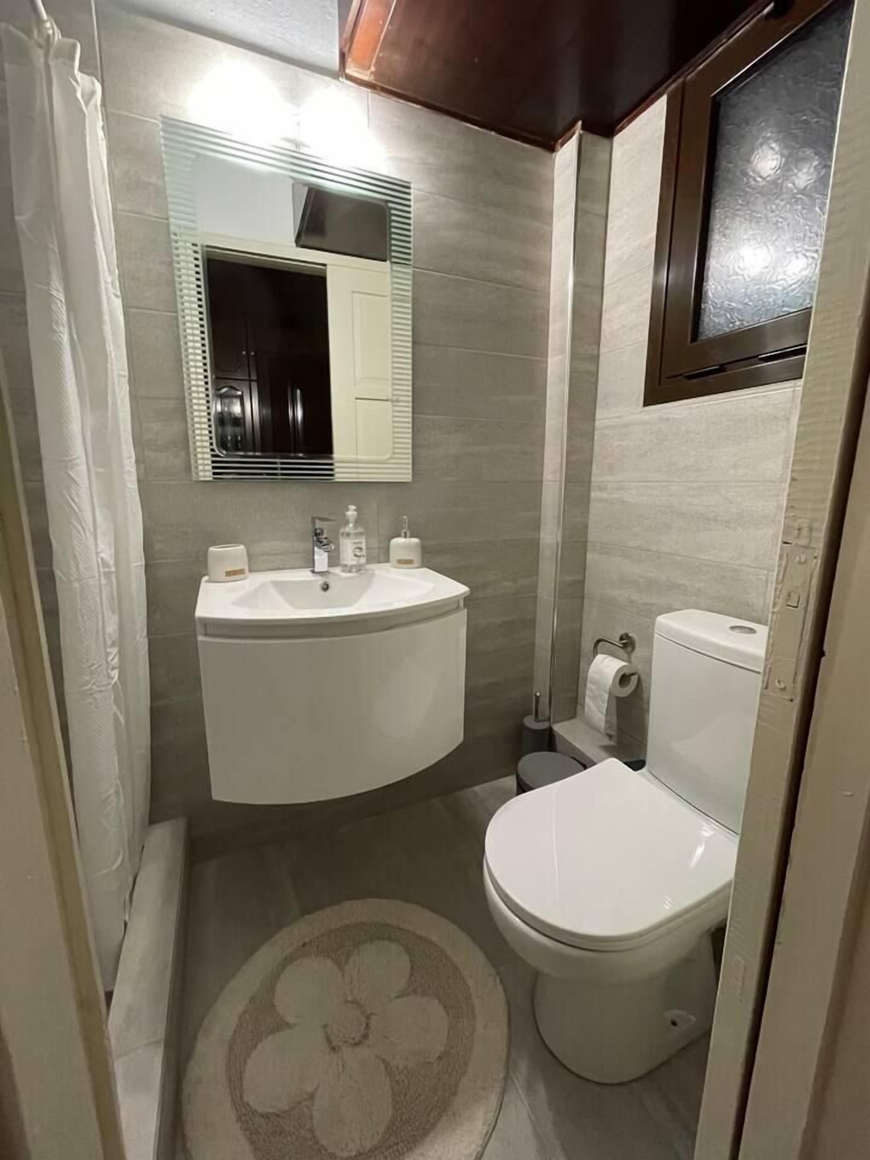 A compact bathroom with a white sink, toilet, and a mirror above the sink.