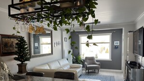 Eine moderne Küche mit Marmorarbeitsplatte, einem weißen Sofa, einem grauen Sessel und einem Essbereich mit einem kleinen Tisch.