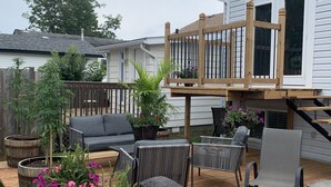 Eine Holzterrasse mit Gartenmöbeln, einer Steinhlaterne und Topfpflanzen.