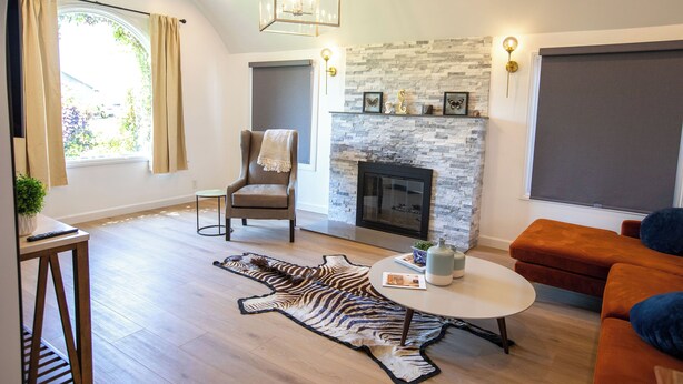 A living room with a fireplace, a round coffee table, a sofa, and a zebra rug.