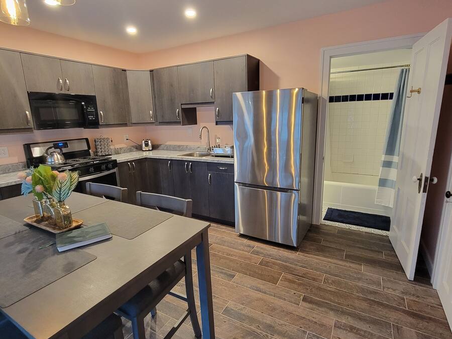 A modern kitchen with dark cabinets, stainless steel appliances, and a wooden dining table.