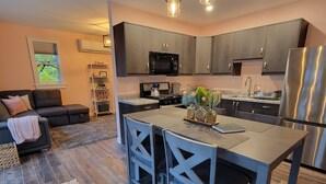 Una cocina moderna con armarios oscuros, un refrigerador de acero inoxidable y una isla central con taburetes de bar.