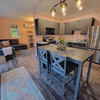A modern kitchen with dark cabinets, a stainless steel refrigerator, and a central island with bar stools.