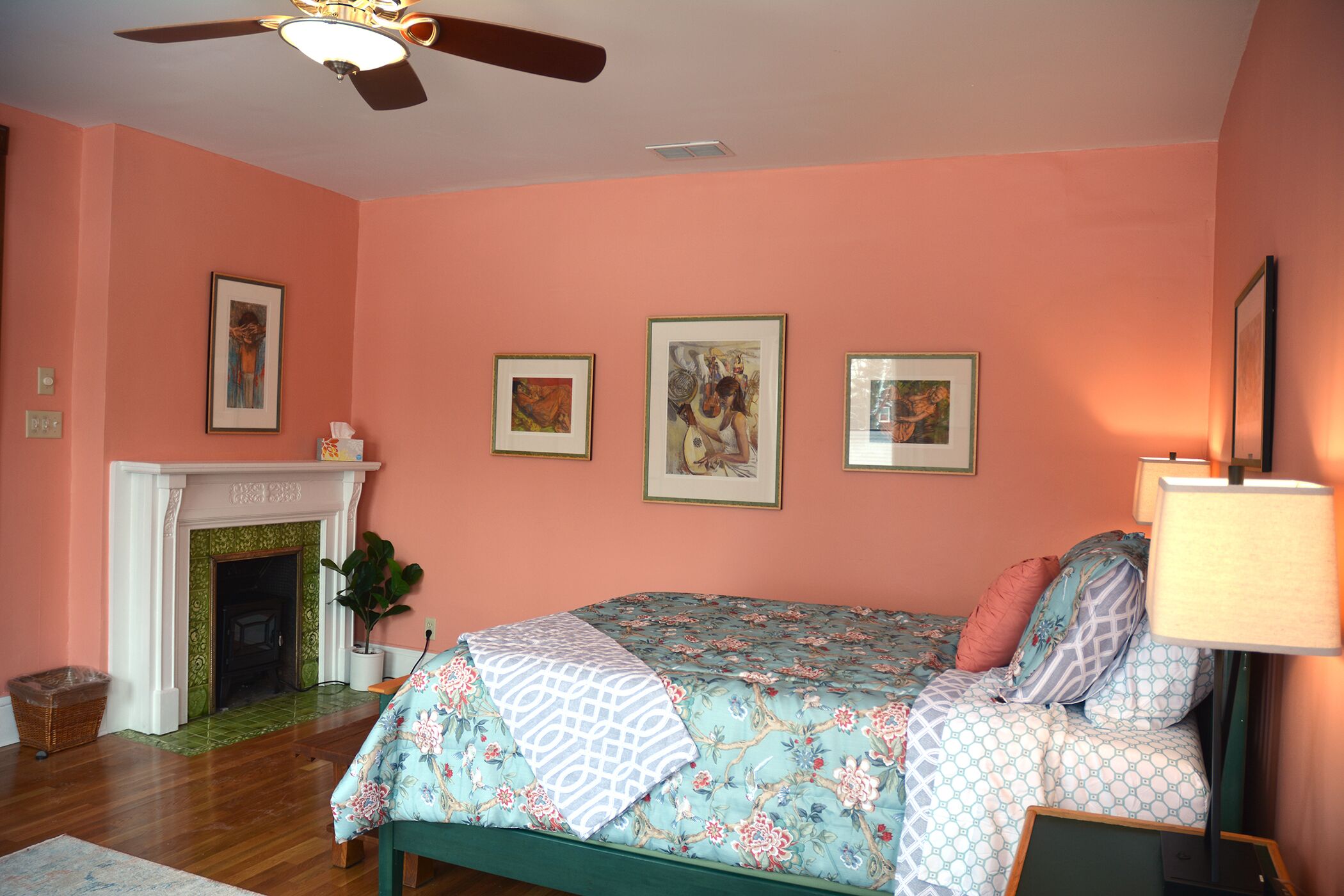Un dormitorio con cama, chimenea y cuadros en la pared.
