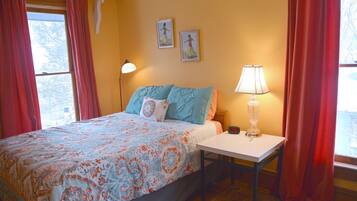 Une chambre à coucher avec un lit, une table de chevet avec une lampe et deux tableaux encadrés au mur.