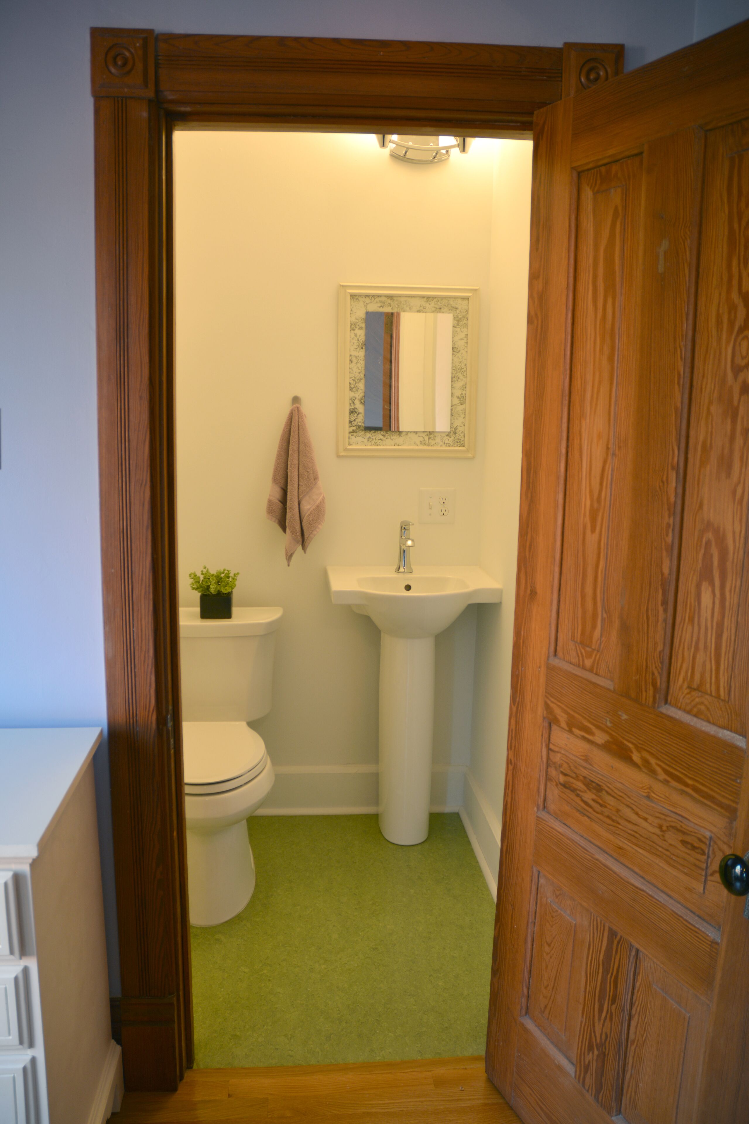 A bathroom with a toilet, sink, and a mirror above the sink.