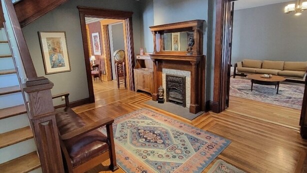 Un salón espacioso con una escalera de madera, una chimenea y un tapete grande.