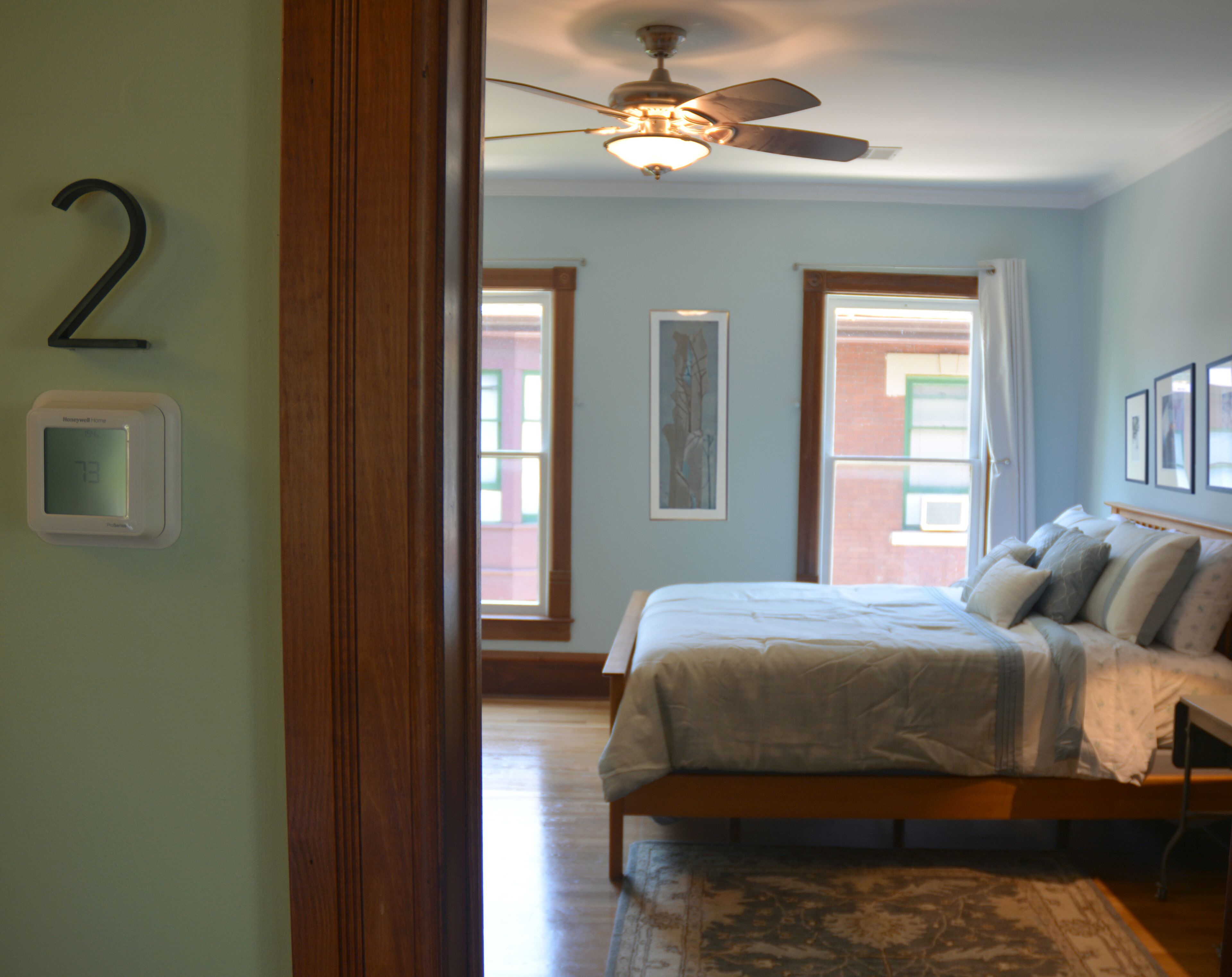 Un dormitorio con cama, ventilador de techo y vista al exterior.