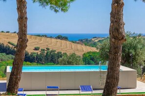 Area piscina con vista sul mare, immersa nel verde.