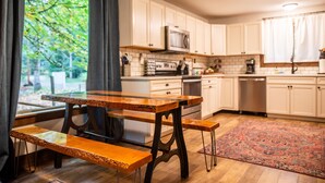 Una cocina con armarios blancos, una mesa de madera y un tapete rojo.