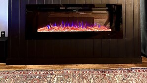 Una chimenea con un televisor encima, un estante de madera y un cuadro enmarcado.