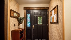 Una puerta negra con un panel de vidrio decorativo, un letrero de bienvenida y un tablón de anuncios.