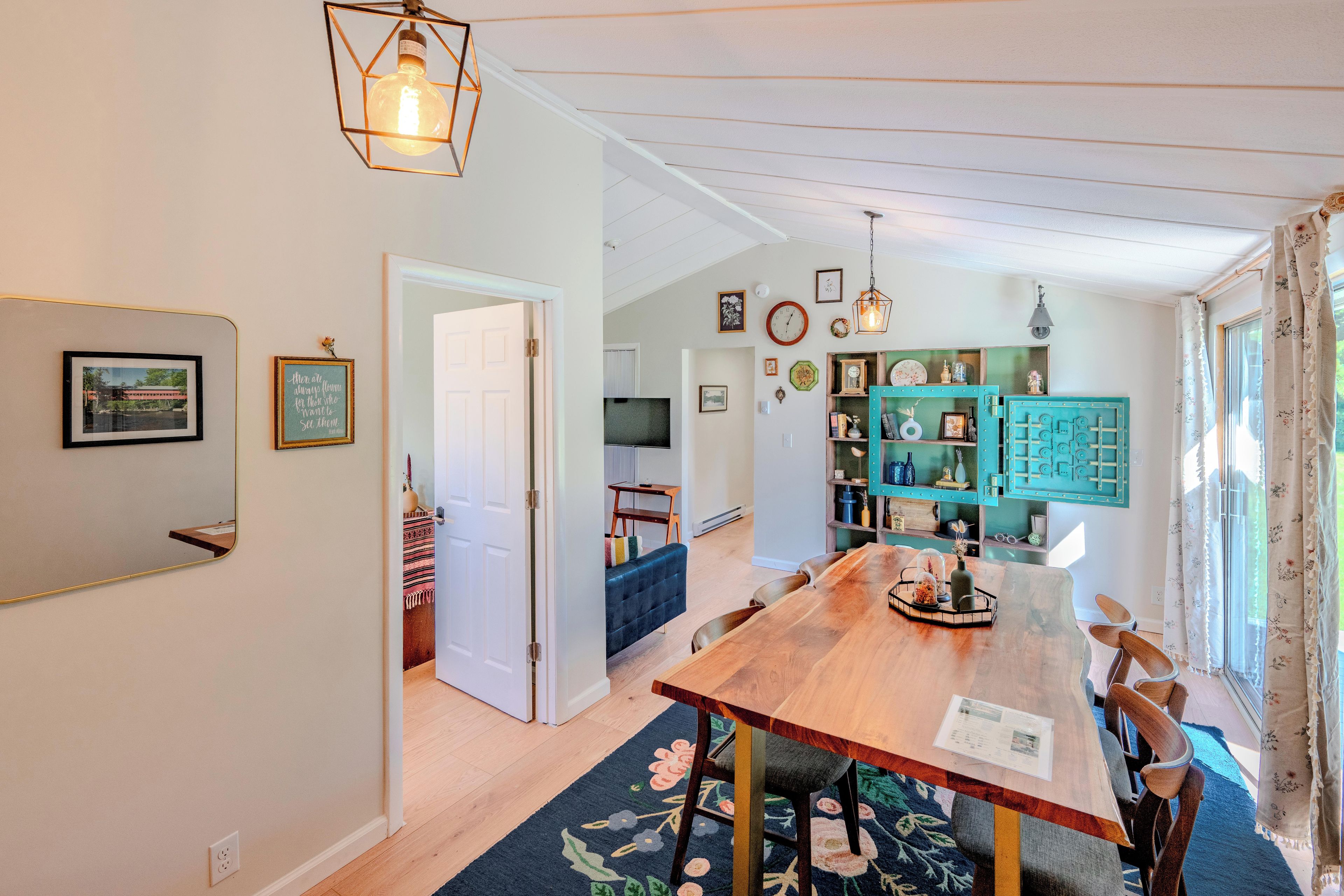 A dining area with a wooden table, chairs, and a floral rug.