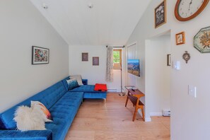 A modern living room with a blue sectional sofa, a flat-screen TV, and a wooden floor.