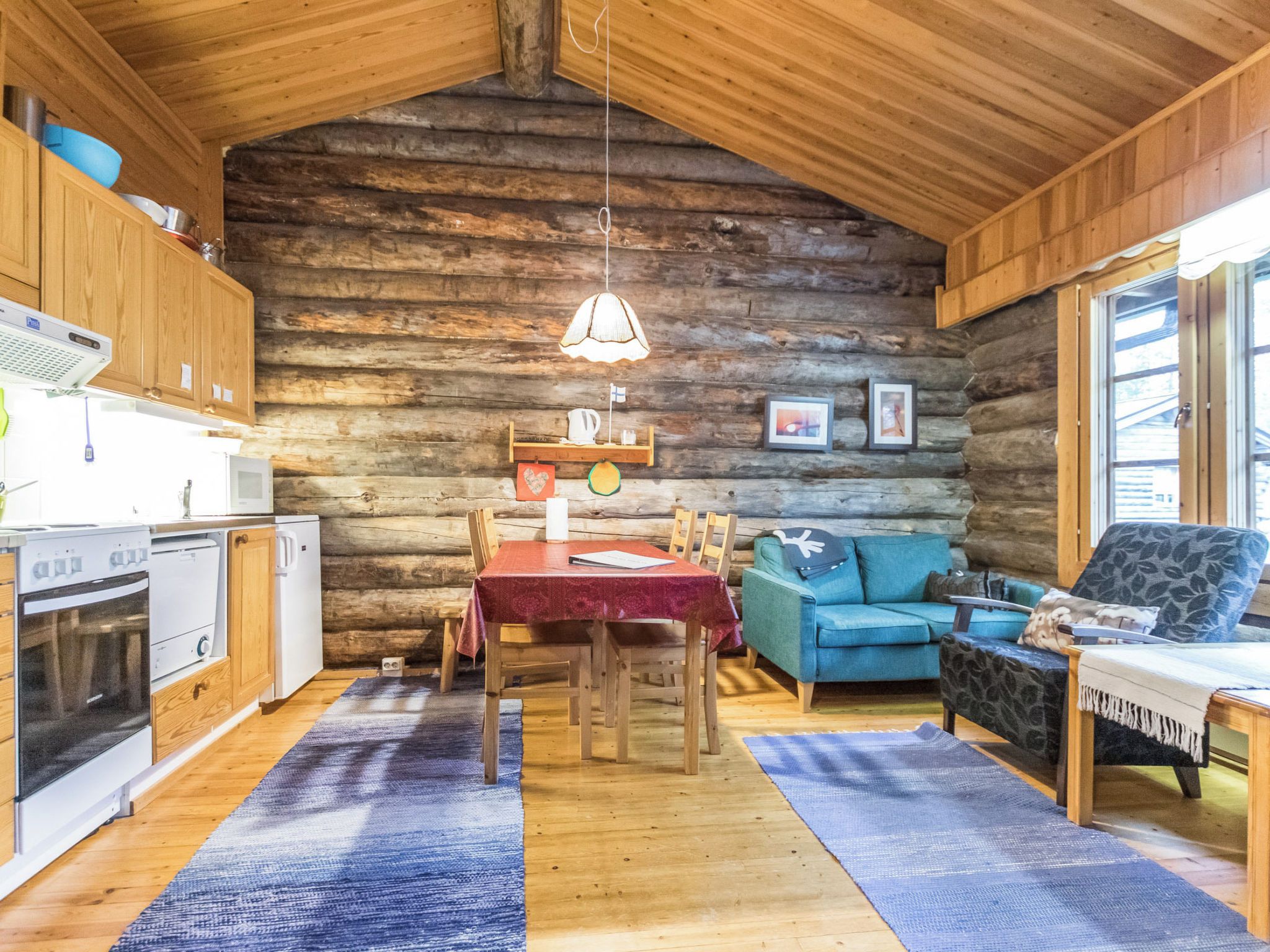 A log cabin interior with a kitchen, dining area, and seating space.