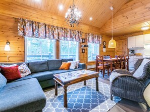 A cozy cabin interior with a sofa, dining table, chairs, and a kitchen area. - Tulikettu 1 by Interhome (Pelkosenniemi)