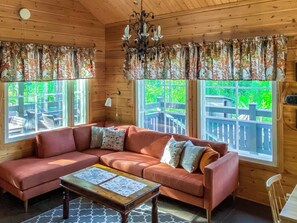 Un interior de cabaña acogedor con un sofá seccional, una mesa de centro de madera y un candelabro.