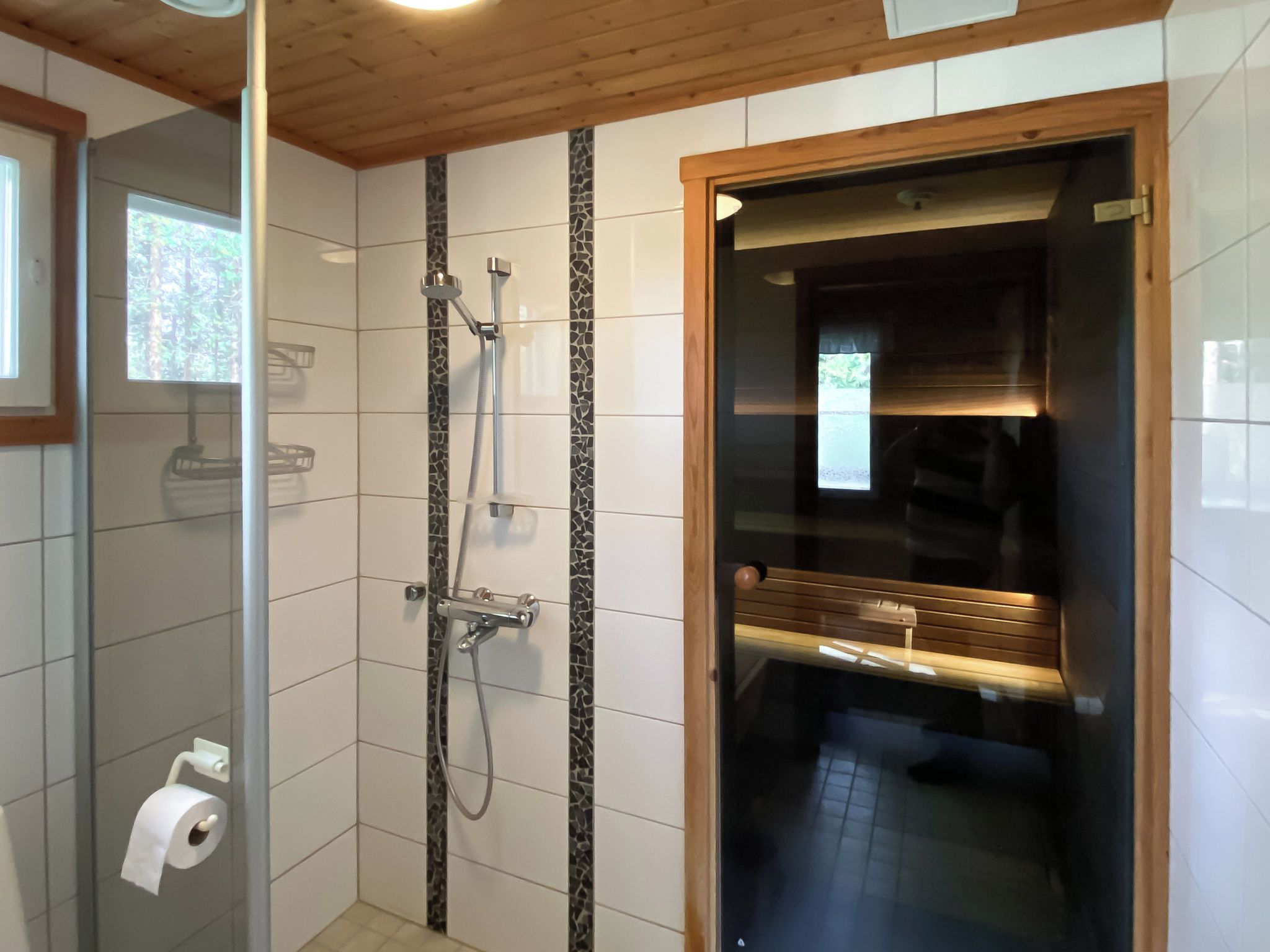 Un baño con ducha, inodoro y un banco de madera.