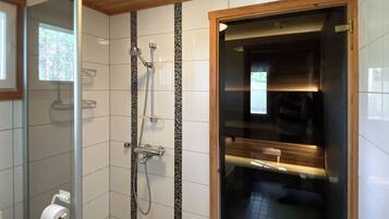 Un baño con ducha, inodoro y un banco de madera.
